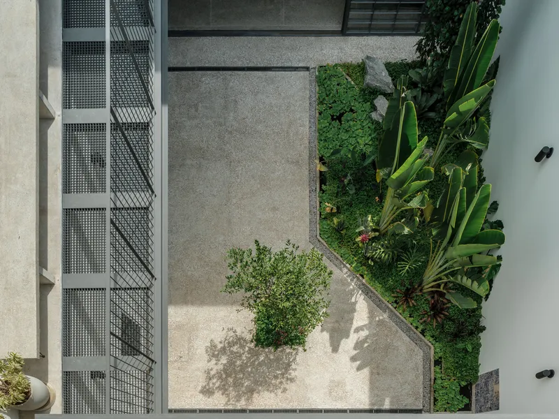 Overhead view of the courtyard showing concrete pavers, planted beds, and perforated metal stair