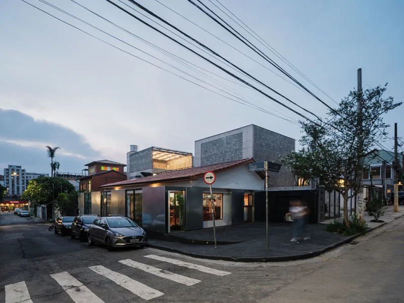 Street corner view of the dark metal and glass facade with overhead power lines at dusk