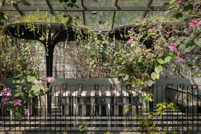 Upper level dining counter backed by a planted wall with flowering vines and glass enclosure