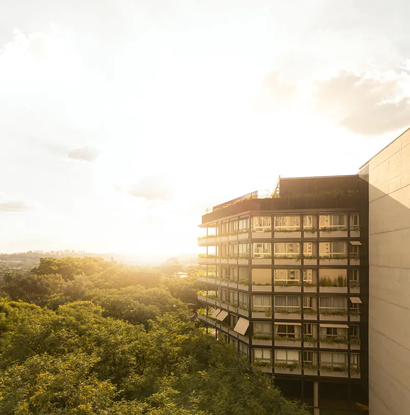 Glass and concrete facade with continuous balconies overlooking a forested landscape at sunset