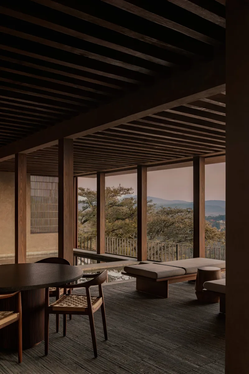 Interior living space with exposed timber ceiling beams and sliding glass doors opening to mountain views at dusk