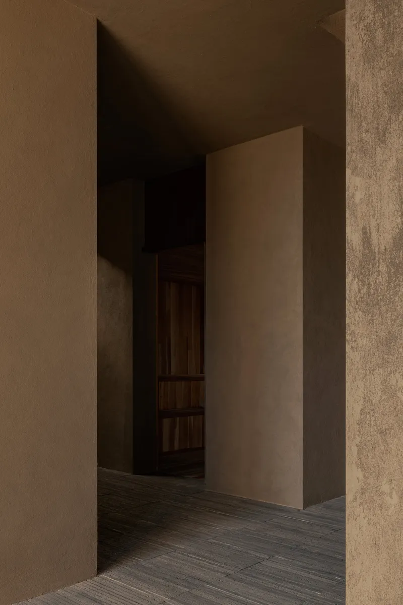 Narrow corridor with textured plaster walls and a freestanding partition in warm ambient light