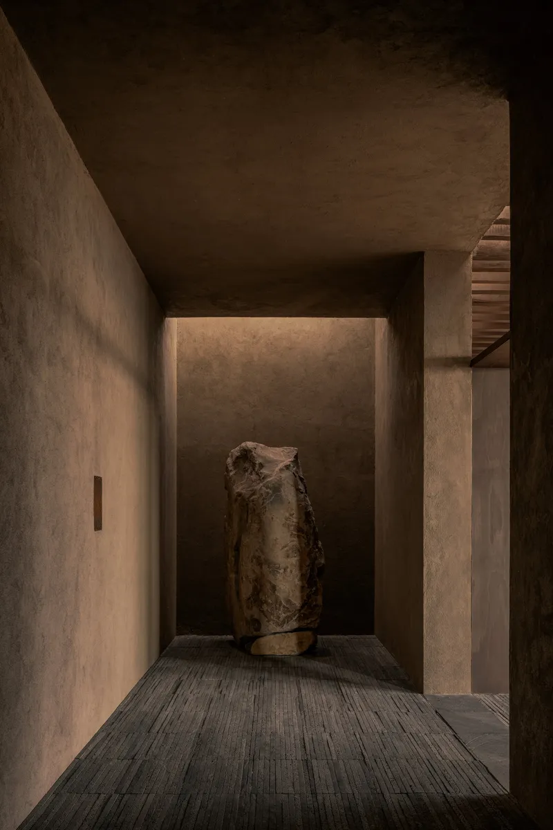 Recessed alcove with backlit wall displaying a weathered ceramic vessel on timber decking