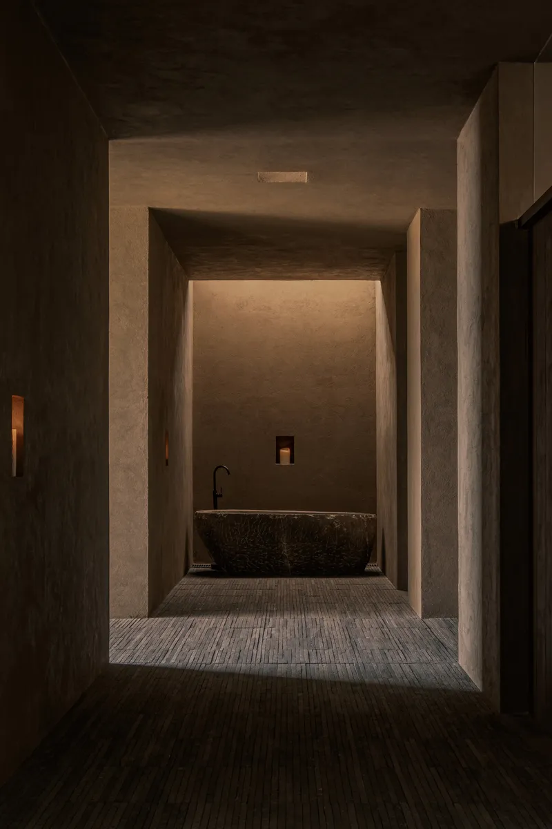 Sequence of framed thresholds revealing a textured stone bathtub in the distance