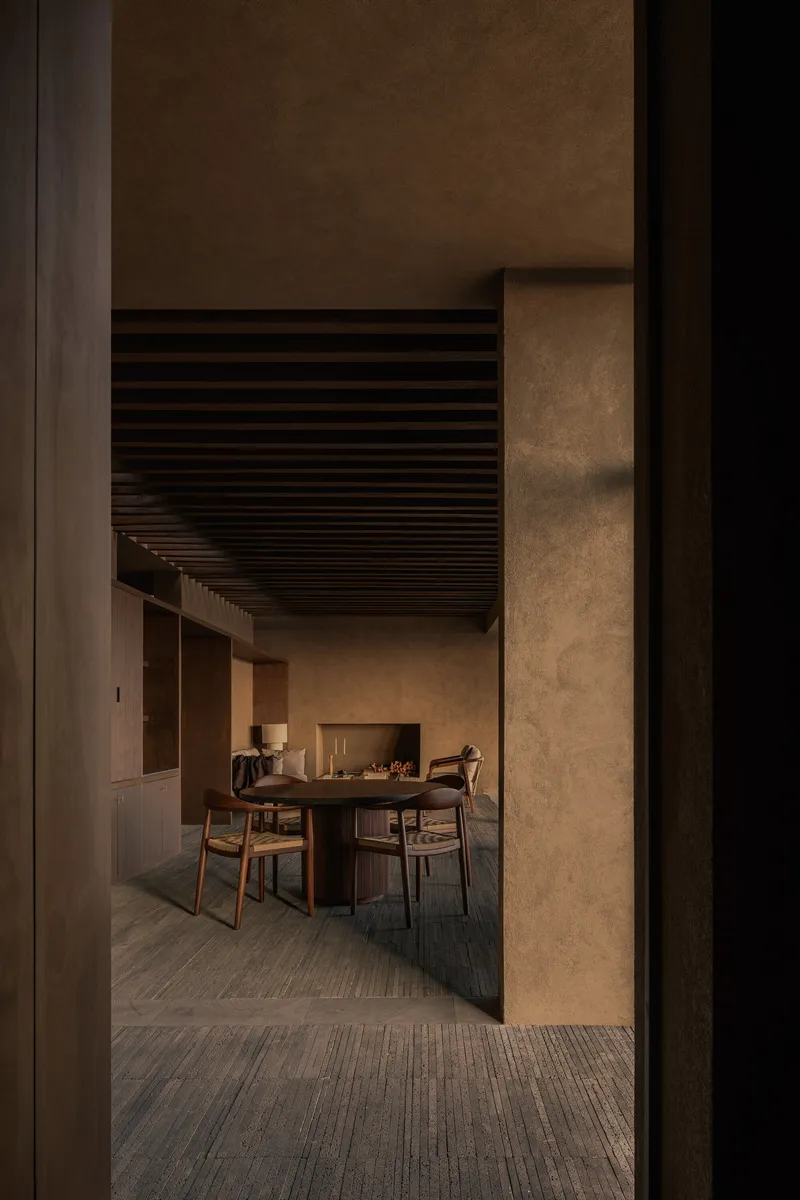 Doorway view into dining space with slatted ceiling and textured concrete walls