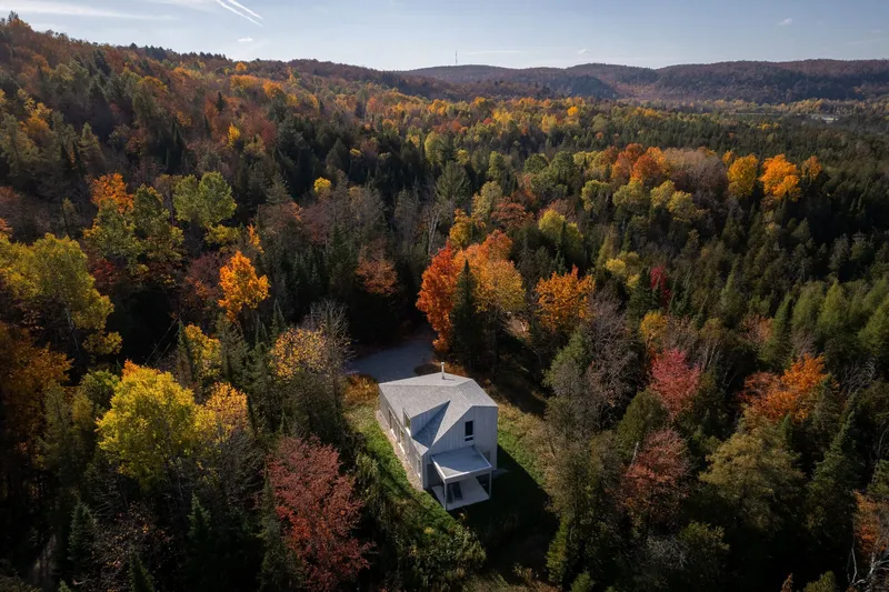 Drone view showing the metal roof and cantilever surrounded by colorful autumn trees