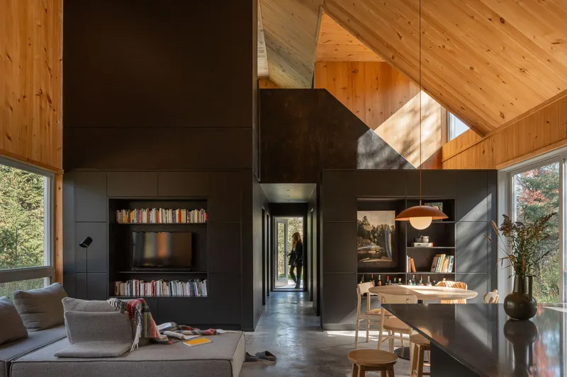 Living space with blackened steel fireplace wall under exposed wood planked cathedral ceiling
