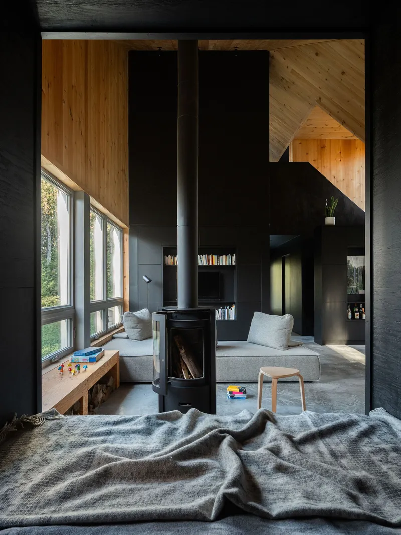 View from bedroom through doorway to living space with wood stove and window seat alcove
