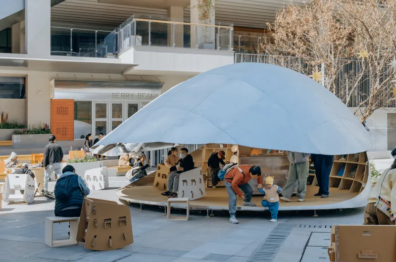 Families gathered beneath the translucent dome canopy supported by radial steel ribs in autumn daylight