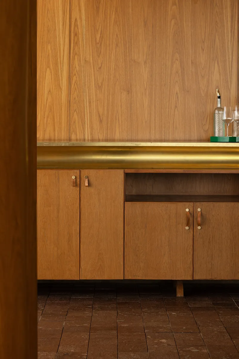 Close-up of walnut cabinetry with brass hardware and integrated LED strip lighting at countertop