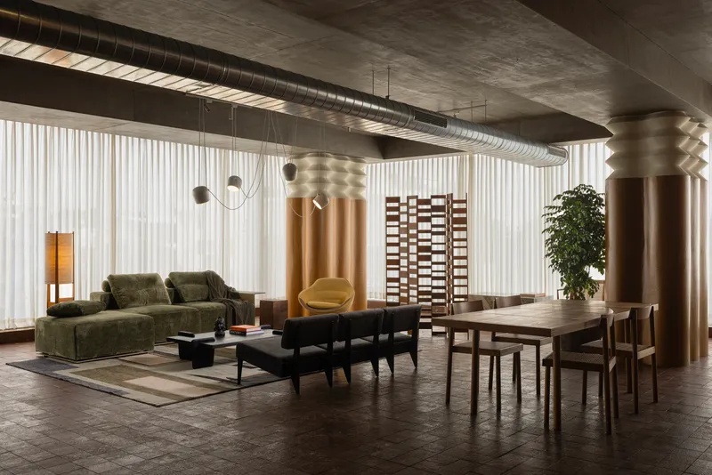 Living and dining area with exposed ductwork, bronze-clad columns, and checkered room divider screen