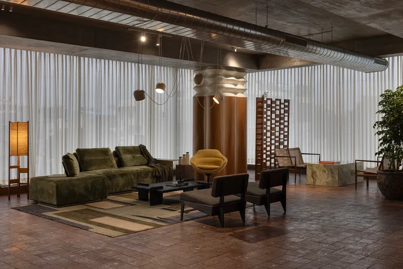 Open lounge space with board-formed concrete ceiling and exposed ductwork running along the beam