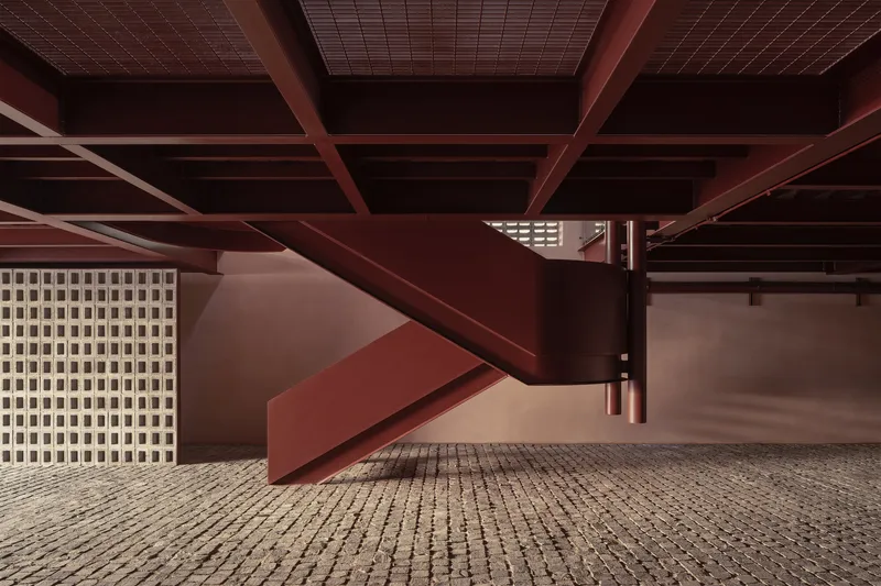 Covered ground-level parking area with exposed steel beams and perforated block screen wall