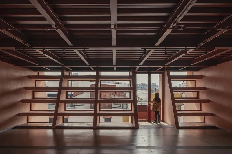 Interior library space with exposed timber ceiling beams and a figure at the window