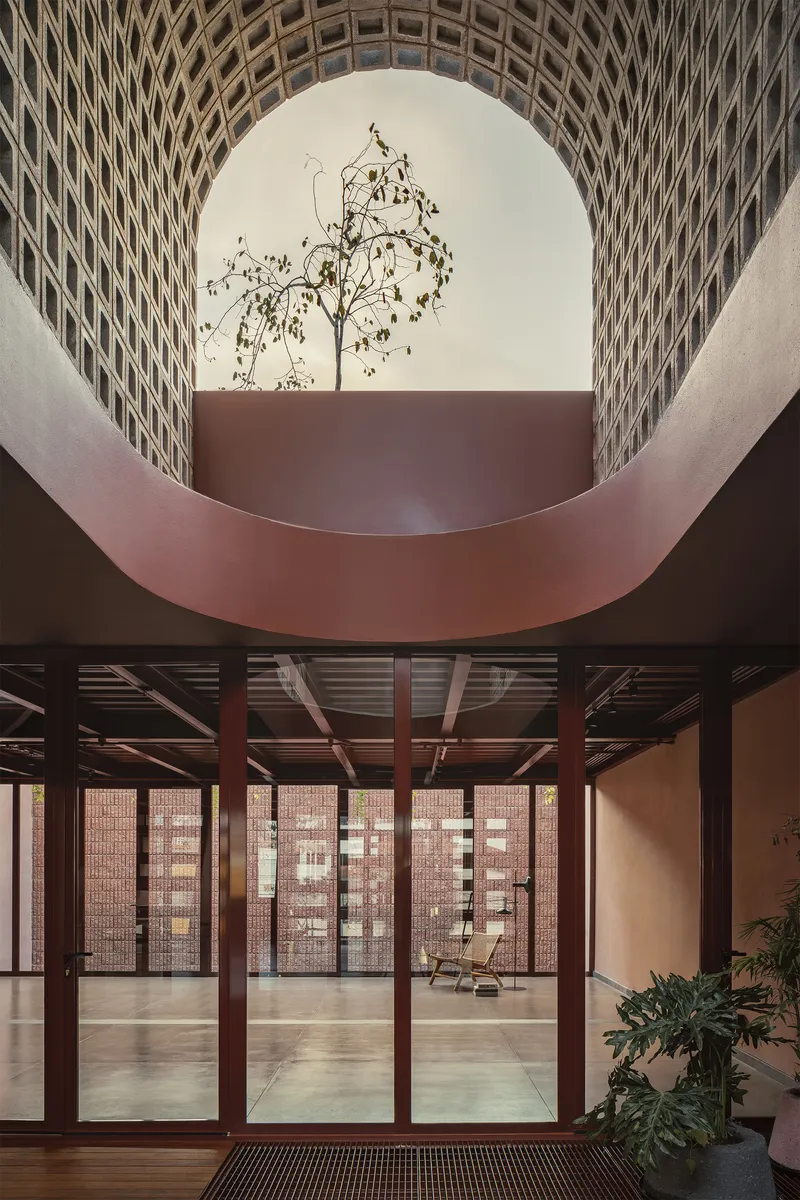 Curved void framing a tree with perforated brick screen and glazed doors below