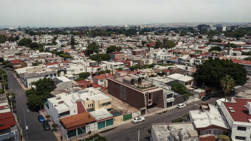 Aerial view of the vaulted brick structure and corrugated metal volume rising above the surrounding neighborhood rooftops