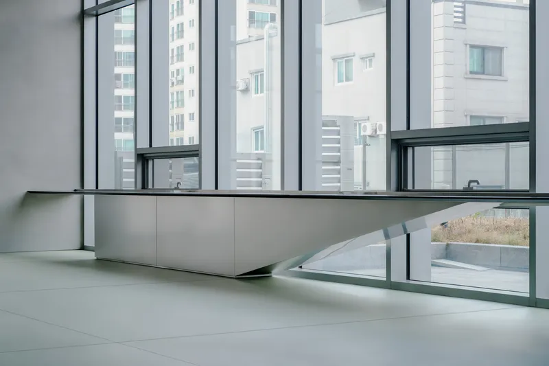Low angled view of a continuous bench below full-height glazing overlooking adjacent tower blocks