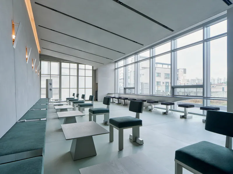 Interior lounge with floor-to-ceiling glazing overlooking neighboring towers under overcast daylight