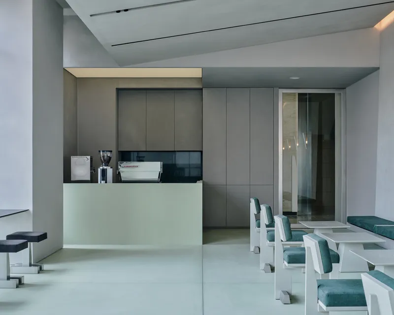 Service counter with integrated espresso machine and frameless glass doorway to adjacent space