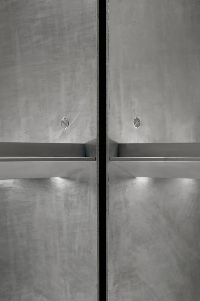 Close-up of concrete wall joint with horizontal metal ledge and integrated lighting below
