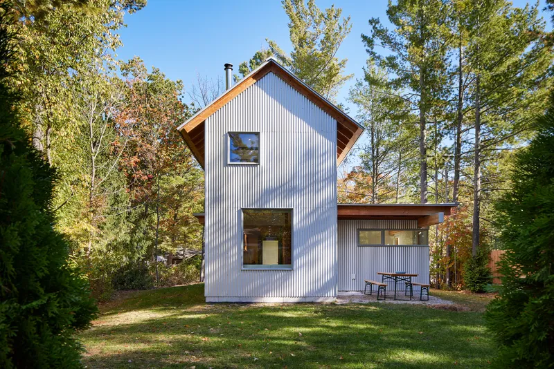 Rear facade showing corrugated metal cladding and single-story wing with outdoor furniture on grass