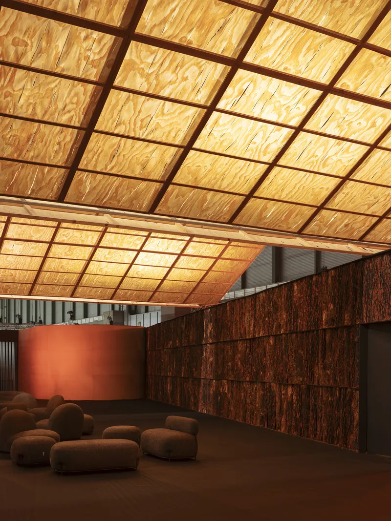 Close view of the translucent plywood panel grid ceiling sloping downward past a terracotta cylindrical wall