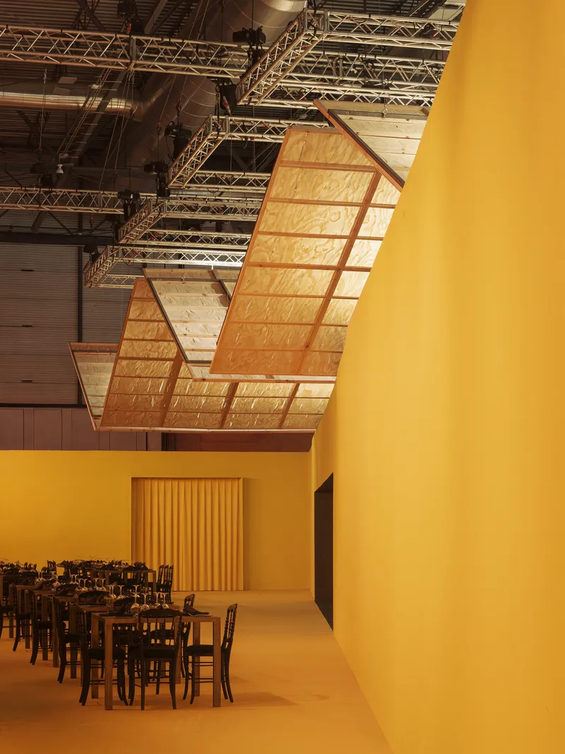 Curved suspended ceiling panel beside a yellow-painted wall and doorway with vertical timber slats