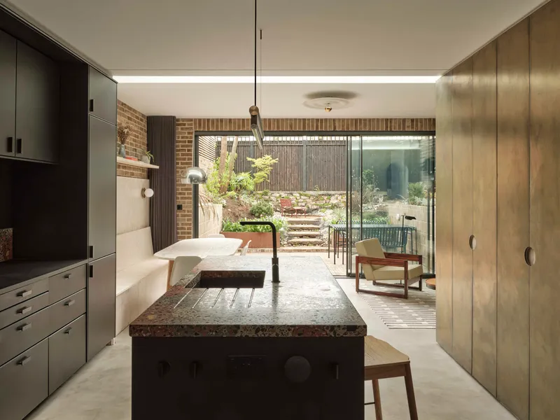 Kitchen island with terrazzo countertop looking through to the planted rear garden with timber steps
