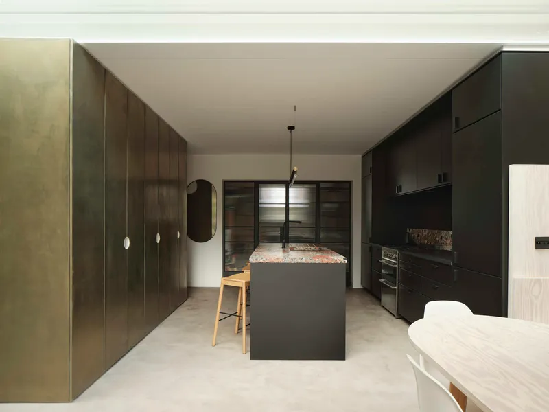 Kitchen with dark timber cabinetry, terrazzo island bench and pale polished concrete flooring