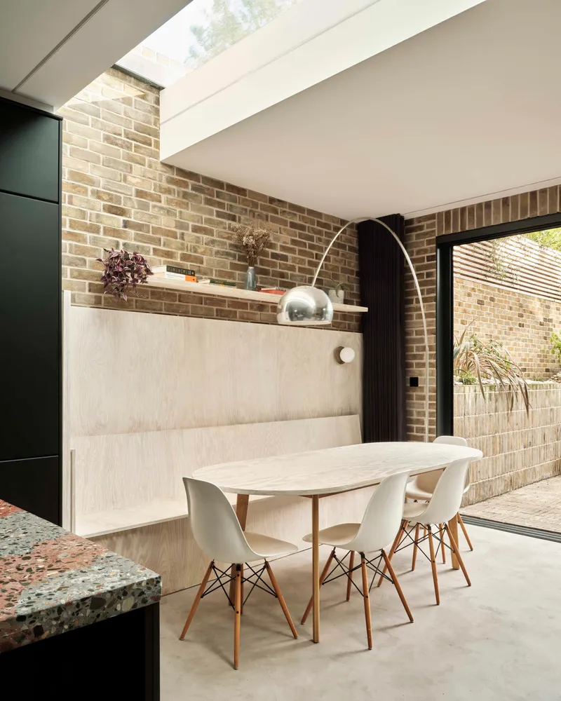 Dining area with exposed brick walls and linear skylight bringing daylight into interior