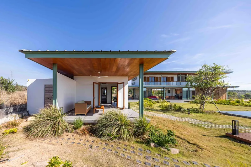 Covered entry pavilion with timber ceiling and planted beds of ornamental grasses in the foreground