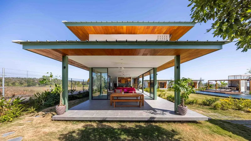 Covered outdoor pavilion with exposed timber soffit and steel columns framing the planted courtyard beyond