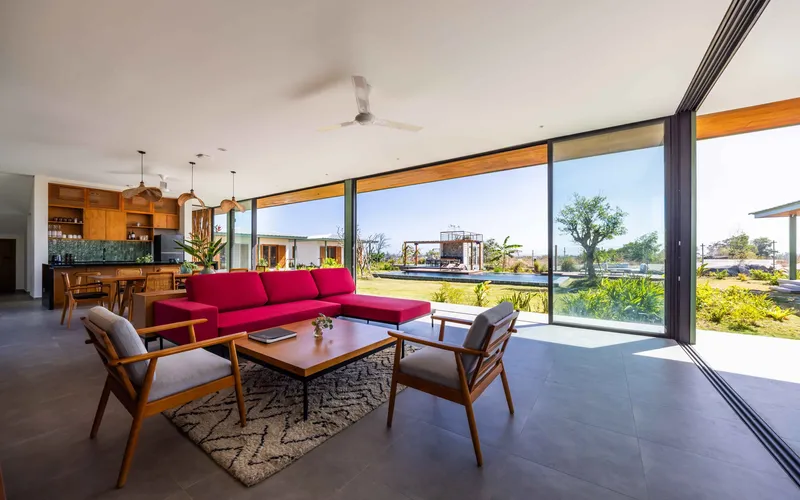 Open-plan living room with floor-to-ceiling glazing overlooking the landscaped grounds and pool pavilion