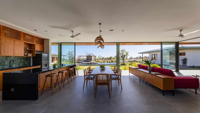 Combined dining and living space with continuous glazing opening to the garden and distant structures