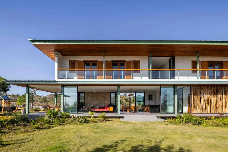Garden facade with broad overhanging roof, timber soffits, and floor-to-ceiling glazing framing the living spaces