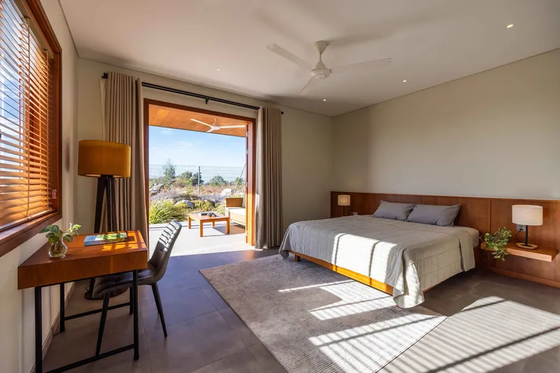 Bedroom with sliding glass doors opening to terrace, timber joinery and striped shadow patterns