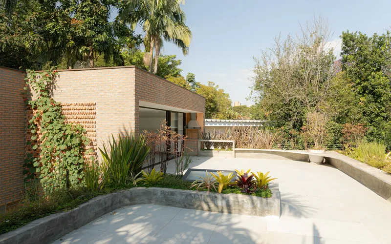 Exterior terrace with curved concrete planters and brick walls beneath a pergola structure