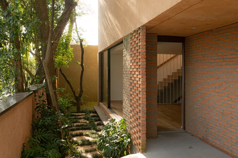 Courtyard entry with brick walls, timber soffit, and stepping stones through planted ground cover