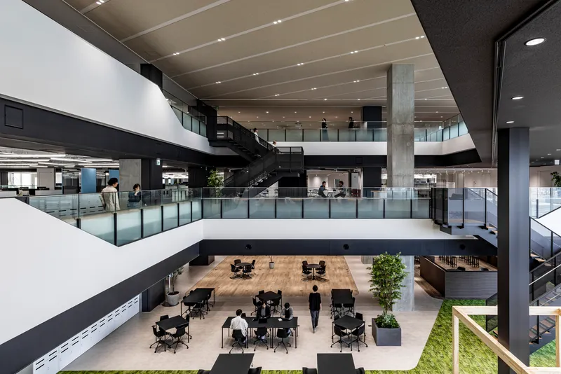 View down into a multi-story atrium with glass guardrails and a person walking below