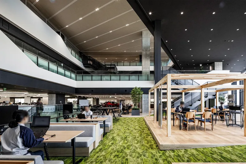 Interior workspace showing a sloped artificial grass feature between seating areas and timber pergola structure