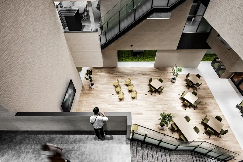 Top-down view of an atrium floor with workers at scattered tables beside a concrete column