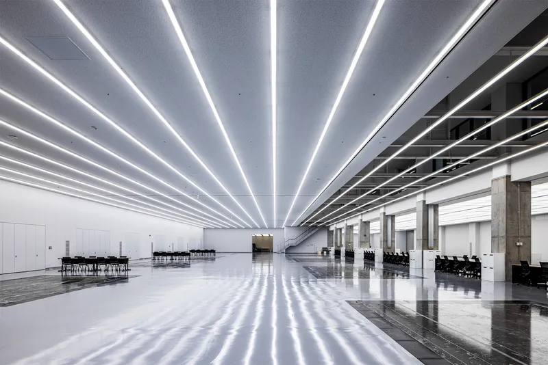 Expansive interior hall with parallel LED light strips radiating across the polished floor and ceiling