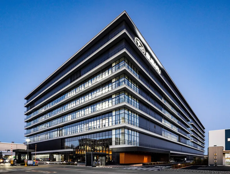 Horizontal banded facade with alternating glass and solid panels beneath a clear blue sky