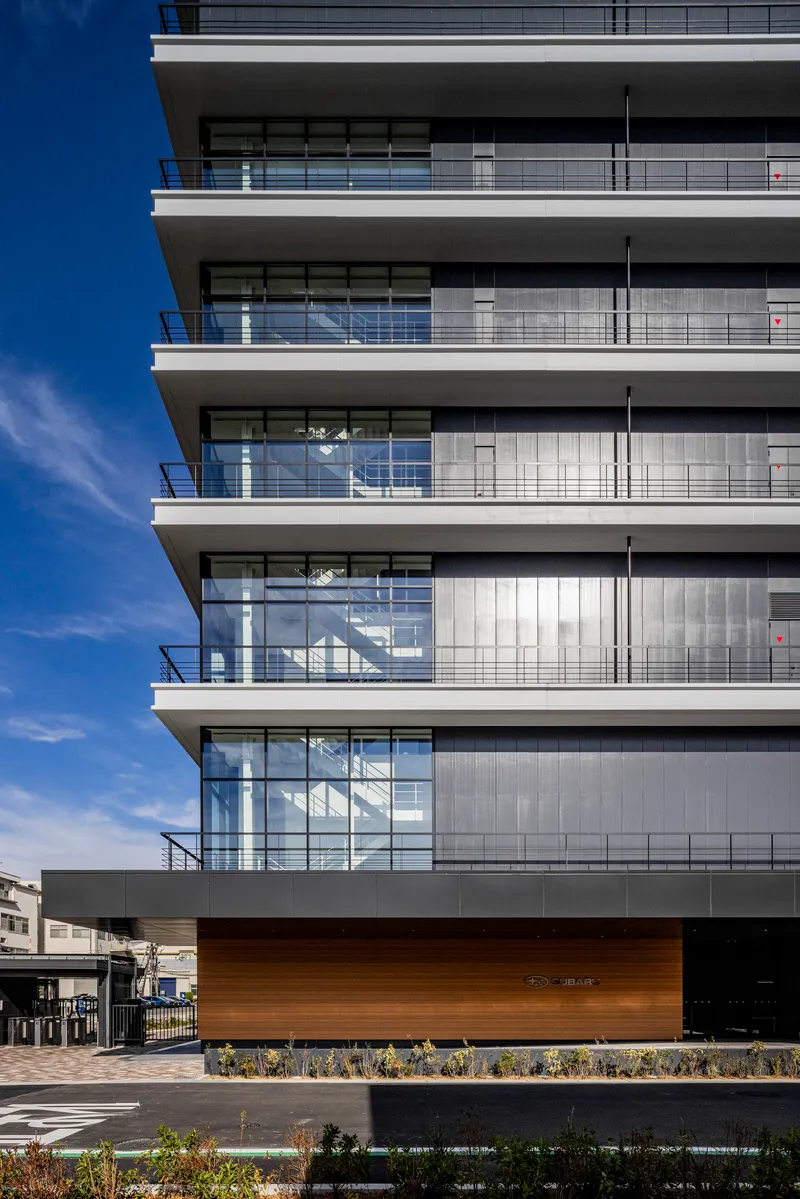 Stacked balconies with glass and solid cladding above a timber-clad base and planted bed
