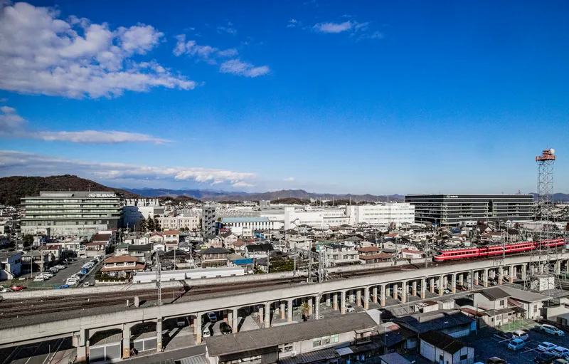Elevated view across rail lines and residential rooftops toward the horizontal banded volumes