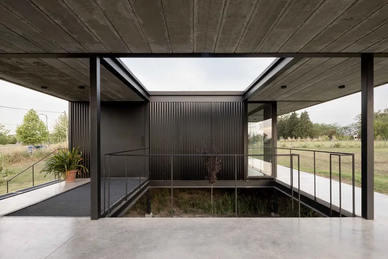 Interior courtyard framed by timber soffit and corrugated metal walls with planted bed below