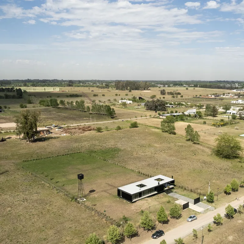 Aerial view of the metal-roofed structure among young trees and a water tower in rural farmland