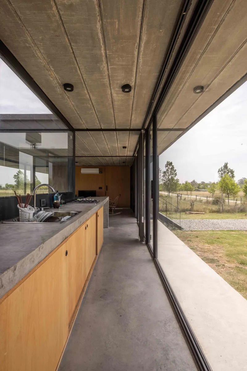 Interior kitchen corridor with timber cabinetry and concrete ceiling panels beneath sliding glass walls