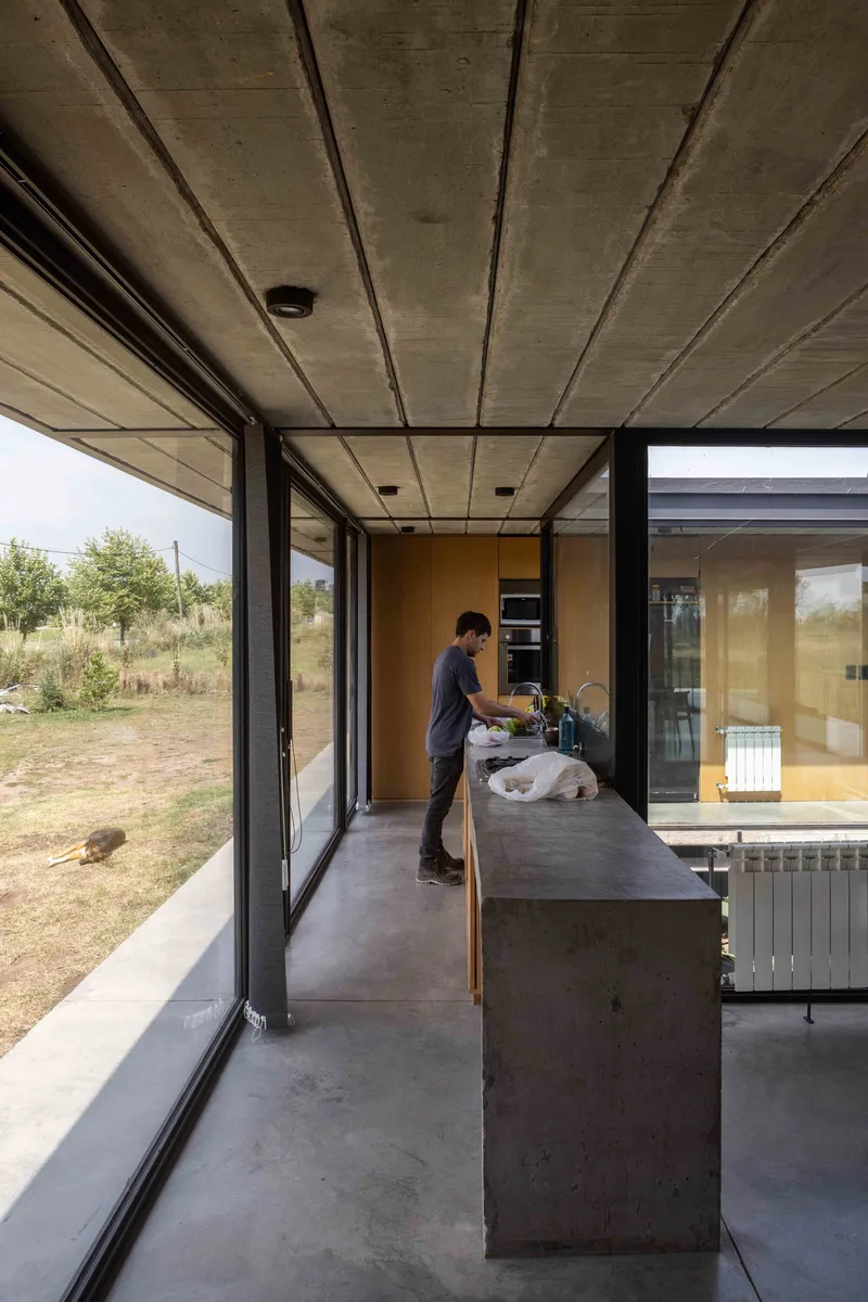 Kitchen with polished concrete island and two occupants cooking beneath exposed concrete soffit panels