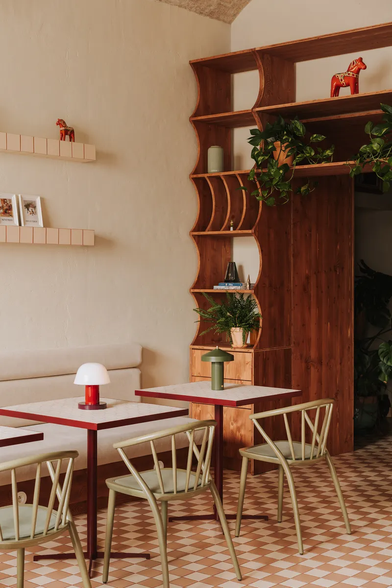 Dining tables with curved timber shelving displaying potted plants and drawers beneath the shelves